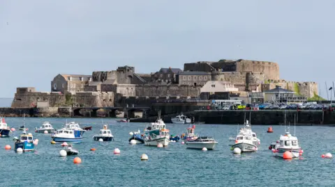 BBC Castle Cornet is a large island castle in Guernsey, with boats in front in the sea