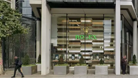 Glass-fronted shop bearing Rolex logo and name in the window 