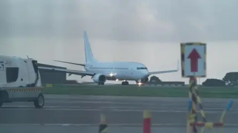 A white jet plane makes its way along the tarmac at Newquay Airport in Cornwall as it prepares to take off.