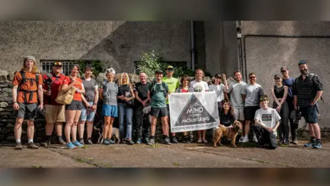 Giles Thurston Image of a group of people. They are holding a white flag with the Mind Over Mountains logo on it.