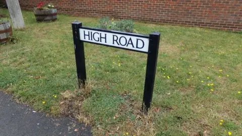 Geographer Sign showing High Road in Epping - plain sign on grass verge