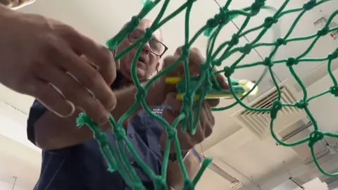 BBC A college tutor demonstrating to a commercial fishing student how to thread a fishing net  at South Devon College