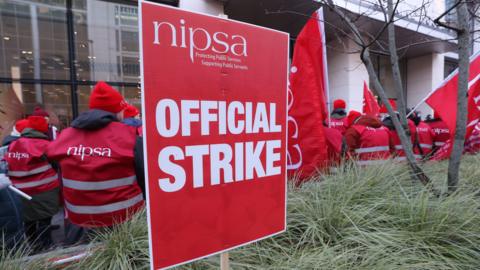 NIPSA union sign reading official strike with NIPSA members pictured in background not facing camera