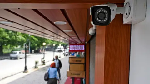 Getty Images This picture taken on May 5, 2022, shows a CCTV camera installed outside a shop at a market in Srinagar. India has ordered all private businesses in Indian-administered Kashmir to install security cameras, a move activists say is aimed at turning one of the world's most militarised places into a surveillance state. 
