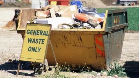 A skip is seen filled with rubbish