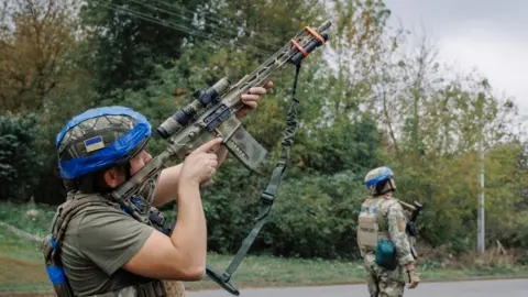 A Ukrainian serviceman looks through the scope of a rifle on September 11, 2024 in Sudzha, Kursk Region, Russia. 
