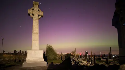 Aisling Kelly A grave stone with the northern lights in the background 