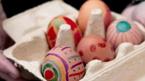 Brightly painted eggs at Easter in a cardboard carton.
