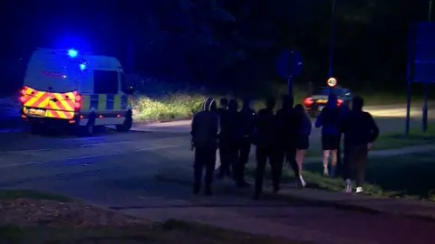 BBC A handful of youths are dispersed from the scene by police