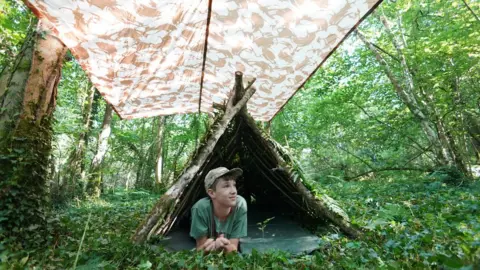 Seth Conway Max lies under woodland shelter and cover