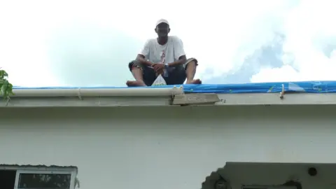 Gemma Handy Devon Warner replaces the missing roof on a relative’s home with tarpaulin.