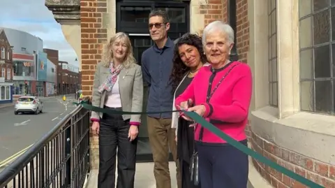 Residents cutting the green ribbon in front of the Old Library. 