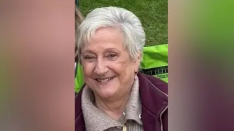 Supplied Edwina Fogg is a woman with short white hair. She is smiling and wearing a brown top and maroon jacket.