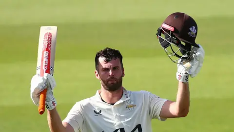 Dom Sibley raises his bat upon reaching 300 for Surrey