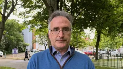 Patrick Lynch is pictured in parade gardens. He is wearing a blue fleece and a blue shirt.