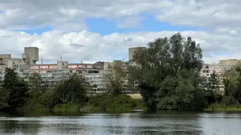 Shaun Whitmore/BBC University of East Anglia, a brutalist building with a large lake to its front. 