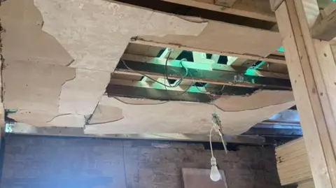 Lancashire County Council A property with bare brick walls and unfinished building work showing an exposed ceiling, light bulb with no light shade and the loft above it   