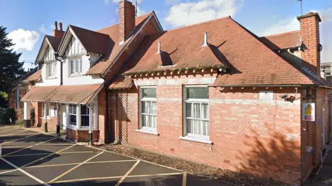 Google The front of Hinckley and District Hospital, in Mount Road, in Hinckley, Leicestershire, with red brickwork with a pitched tile roof.