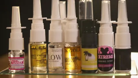 Small bottles of nose tanner. They have white and black cap and colorful labels.