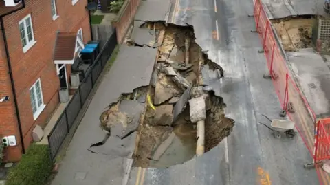 Reuters An aerial view of Godstone High Street showing the sinkholes. The street is cordoned off and houses line either side of the street.