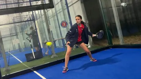 Chloe De La Mare hitting a ball while practising padel in Guernsey