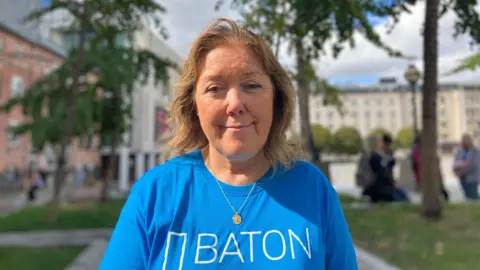 Steve Jones/BBC Kate Cleal, who has mid-length brown hair. She is wearing a blue baton of hope t-shirt.