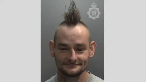 Humberside Police A man with brown hair in a Mohican style in a police custody photo, with a Humberside Police crest watermark on it.