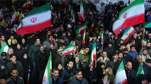 Crowds of people gather in Tehran waving Iranian flags 