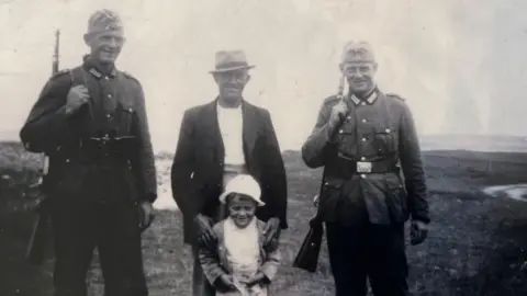 Boy with grandfather flanked by two German soldiers - all smiling