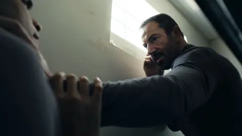 A man pins another man to a wall 