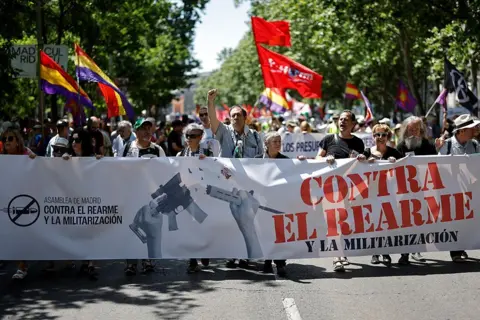 Getty Images Protesters hold a banner reading 'against rearmament and militarisation' during a demonstration for peace and against the rearmament of Spain in Madrid on June 7, 2025