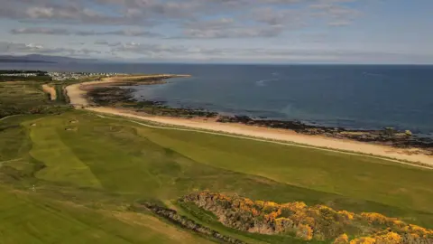 Matthew Harris An aerial picture showing part of Royal Dornoch golf course. There are fairways and bunkers alongside a golden sandy beach and deep blue sea.