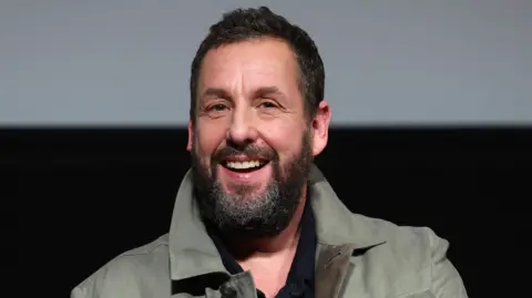 Getty Images Adam Sandler smiling on stage during a Jay Kelly Bafta screening in Los Angeles in November 2025