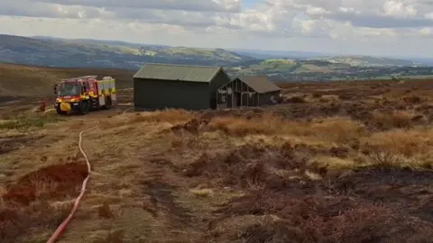 A fire engine in a field with a hose