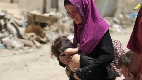 AFP An Iraqi woman carries a child as she flees from the Old City of Mosul on June 20, 2017, during the ongoing offensive by Iraqi forces to retake the last district still held by the Islamic State (IS) group.