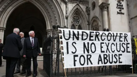 Getty Images Campaigners attach a banner to the entrance of The High Court