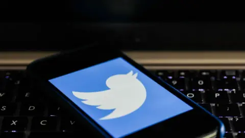 Getty Images Phone with Twitter logo on laptop