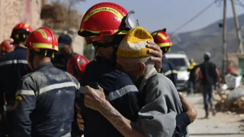 REX/Shutterstock A rescuer comforts an earthquake survivor in the Moroccan town of Amizmiz