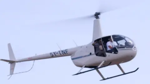 Man throwing seedballs from a helicopter