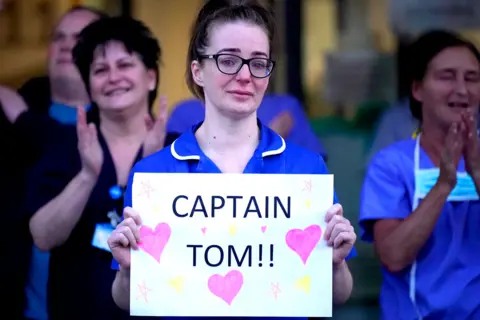 Getty Images A nurse holds a sign saying "Captain Tom"