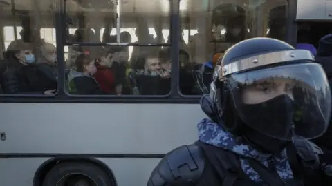 EPA A policeman by a bus of detained protesters in St Petersburg