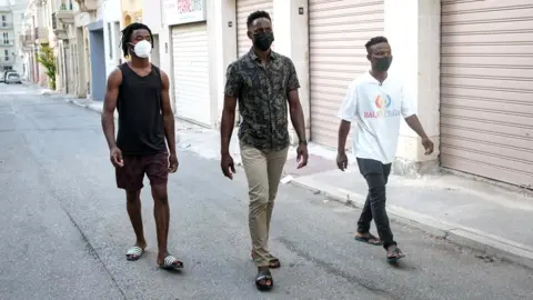 BBC/Joanna Demarco Abdalla, Abdul and Lamin in a street in Malta