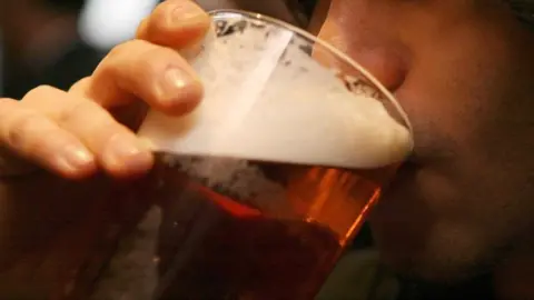 PA Media A man drinking a pint of beer