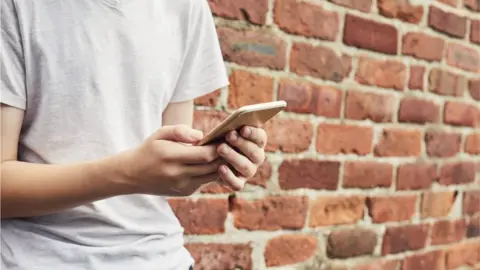 Getty Images Teenage holding a phone