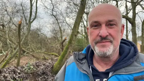 Andrew Turner/BBC Martin Mould stands next to a ditch