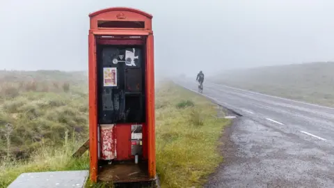 Paul Campbell Old phone box and NC500 cyclist