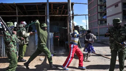 Getty Images An anti-riot policeman beats a man with a stick as police flushes out opposition supporters, who had taken cover in a shack to escape teargas, during demonstrations in the Umoja subururb of Nairobi on November 28, 2017, following a denial of permission by police to the National Super Alliance (NASA) leader to hold a rally concurrently to the inauguration of the country's new president.