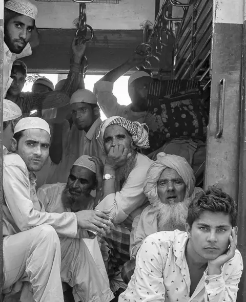 Harshita Mahajan Passengers crowd the entrance to a train.