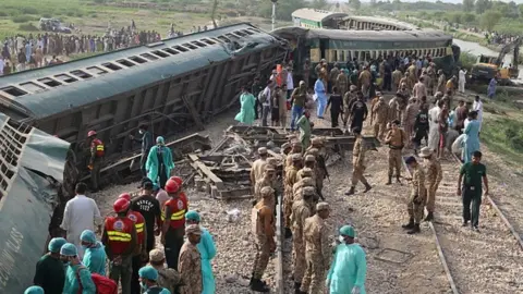AFP Paramilitary rangers and volunteers inspect the carriages at the accident site following the derailment of a passenger train in Nawabshah on August 6, 2023