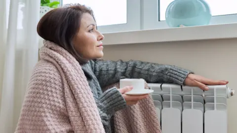 Getty Images Women warms herself at a radiator